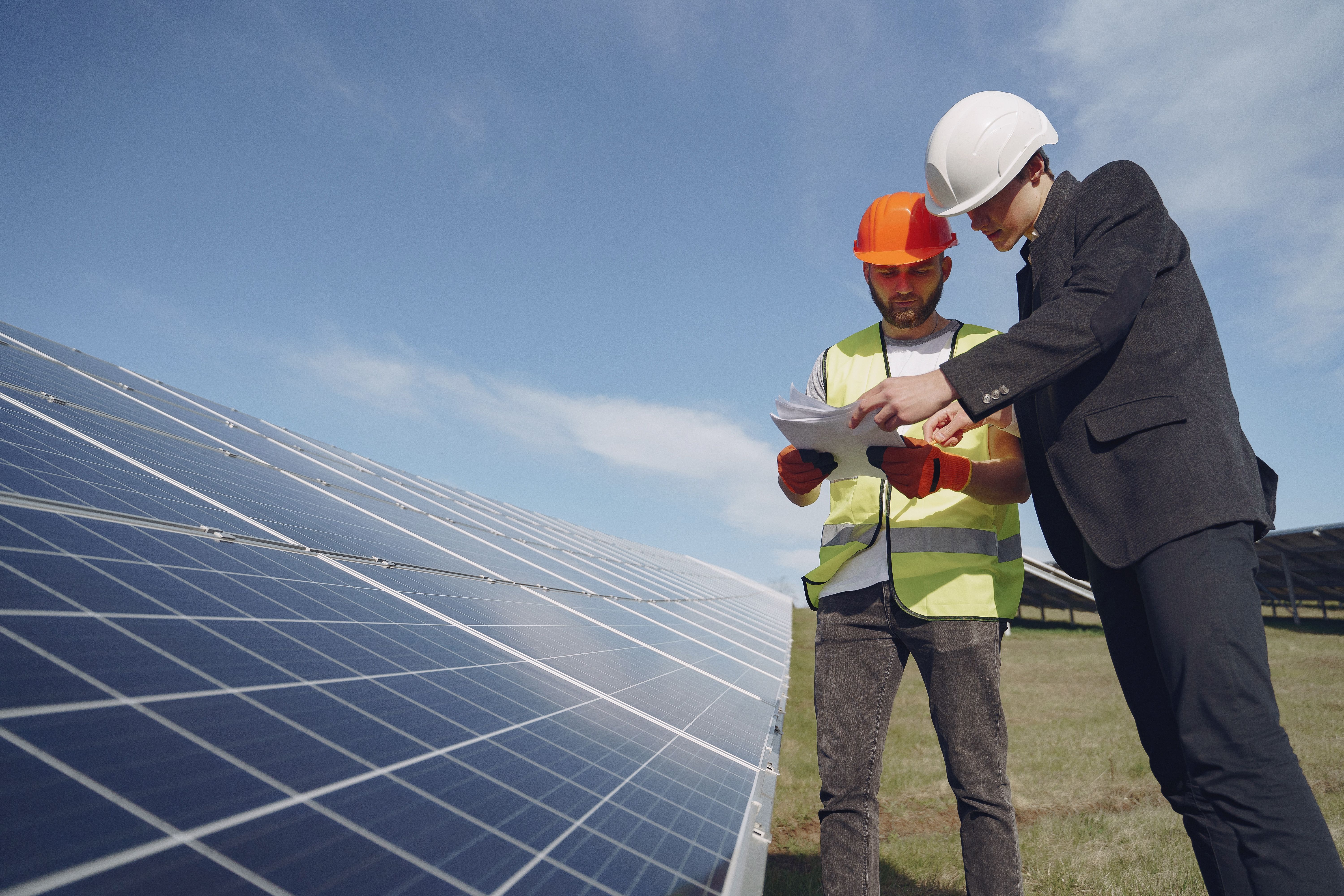Technicians reviewing plans beside a solar array